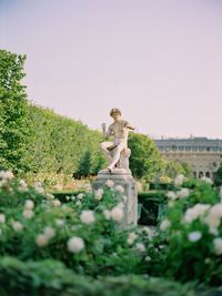 Statue against trees and plants against sky