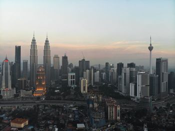 Modern buildings in city against sky during sunset