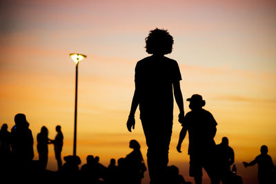 Silhouette people against orange sky