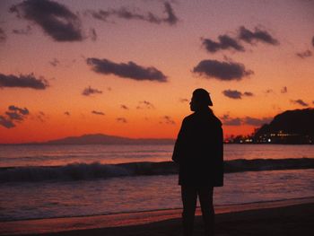 Silhouette man looking at sea against sky during sunset