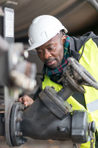 African american mechanic wearing safety equipment checking and inspecting gear train