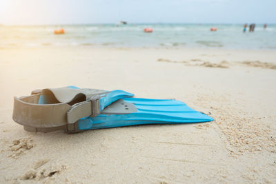 Deck chairs on sand at beach against blue sky