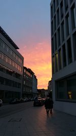 Street amidst buildings against sky during sunset