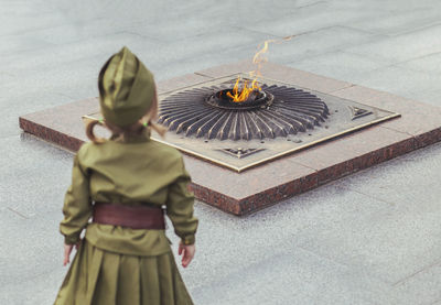 Baby in a soviet military uniform looks at the monument to those killed in world war ii