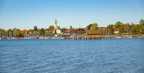 Buildings at waterfront against blue sky