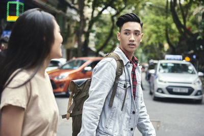 Portrait of young man standing on street in city