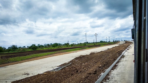 Road amidst field against sky