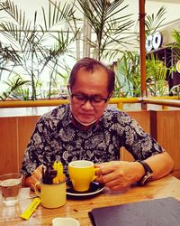 Young woman looking away while sitting on table at restaurant
