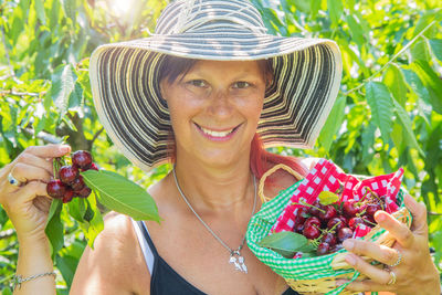 Portrait of a smiling young woman holding strawberry outdoors