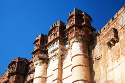 Low angle view of mehrangarh fort against clear blue sky