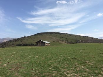 House on field by mountain against sky