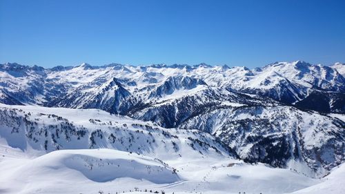 Scenic view of snowcapped mountains against clear blue sky