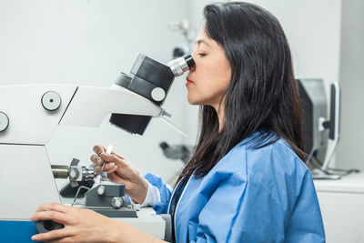 Female scientist placing a sample on a transmission electron microscopy grid