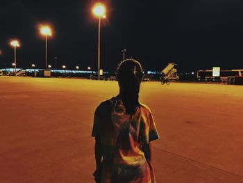 Rear view of man standing on street at night