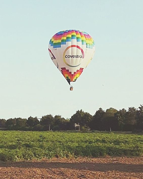HOT AIR BALLOON FLYING OVER LANDSCAPE AGAINST CLEAR SKY
