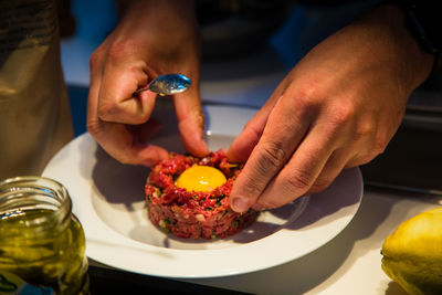 Midsection of man preparing food in plate on table