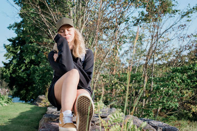 Woman sitting on a wall with her eyes closed enjoying the sunshine