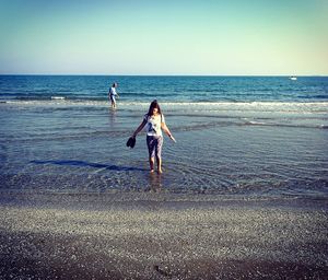 Children on beach against sea against sky