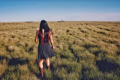 Rear view of woman walking on field