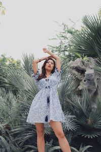 Portrait of young woman standing against plants in park