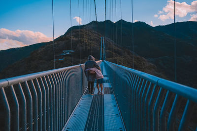Rear view of man walking on footbridge