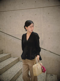 Portrait of young woman standing on footpath