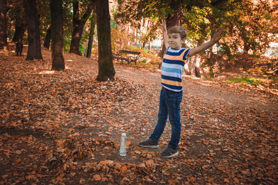 Portrait of smiling boy with arms raised standing in forest
