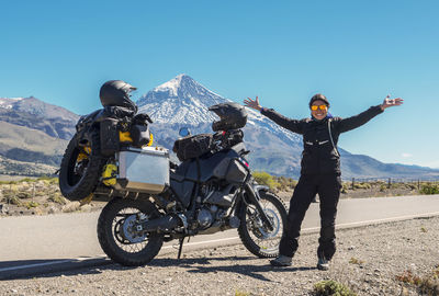 Woman standing next to touring motorbike. lanin volcano in the back