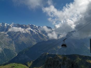 Overhead cable cars over snowcapped mountains against sky