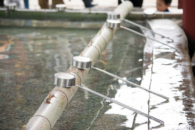 Steel spoons leaning on bamboo over drinking fountain at japanese temple