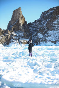 Rear view of man standing on snow covered mountain