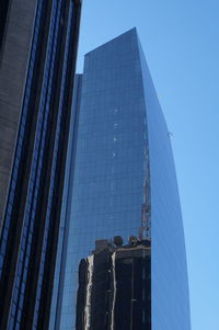 Low angle view of modern glass building against clear blue sky