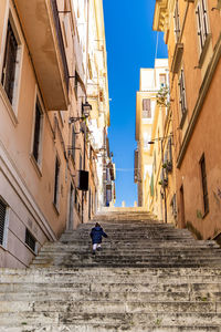 Rear view of girl walking on staircase amidst buildings