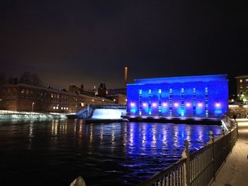 Illuminated bridge over river against sky at night