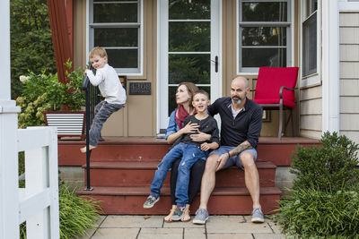 A happy family sit together on front stoop