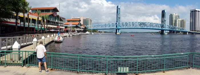 Tourists on bridge against cloudy sky