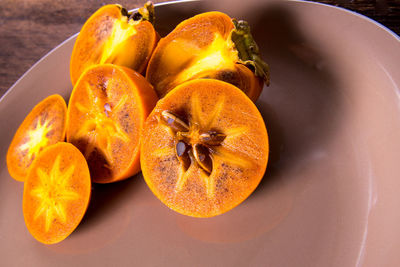 Persimmon cut into halves on a plate on a wooden table,copy space,closeup