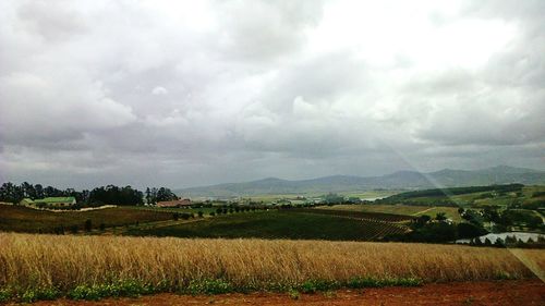 Scenic view of field against cloudy sky