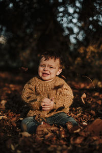 Cute boy sitting on field during autumn