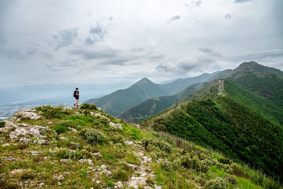 Rear view of man walking on mountain against sky