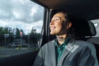 Happy businesswoman sitting in car looking through window