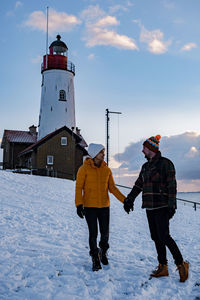 Rear view of men on snowcapped field against sky