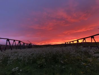 Silhouette bridge over land against sky during sunset