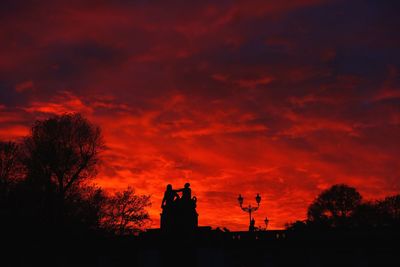 Low angle view of silhouette building against orange sky