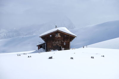 House on snow covered field against sky