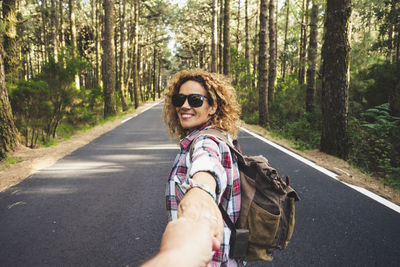 Portrait of woman wearing sunglasses on road in forest