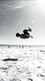 Man jumping on beach against sky