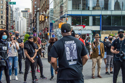 Rear view of people standing on street in city
