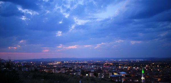 High angle view of illuminated cityscape against cloudy sky