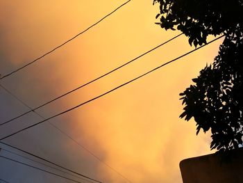 Low angle view of silhouette power lines against sky at sunset